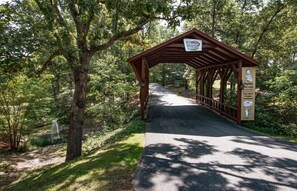 A covered wooden bridge with signage for Branson Cedars and a welcome sign for Nightly Rentals. - Branson | Family Ozarks Retreat | Pool + Fitness (Ridgedale)