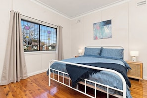 Ein Schlafzimmer mit einem Bett, einem Fenster und einem Bild an der Wand.