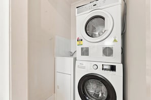 Eine gestapelte Waschmaschine und ein Trockner mit Bedienfeld, Energieeffizienz-Etikett und Sicherheitshinweisen.