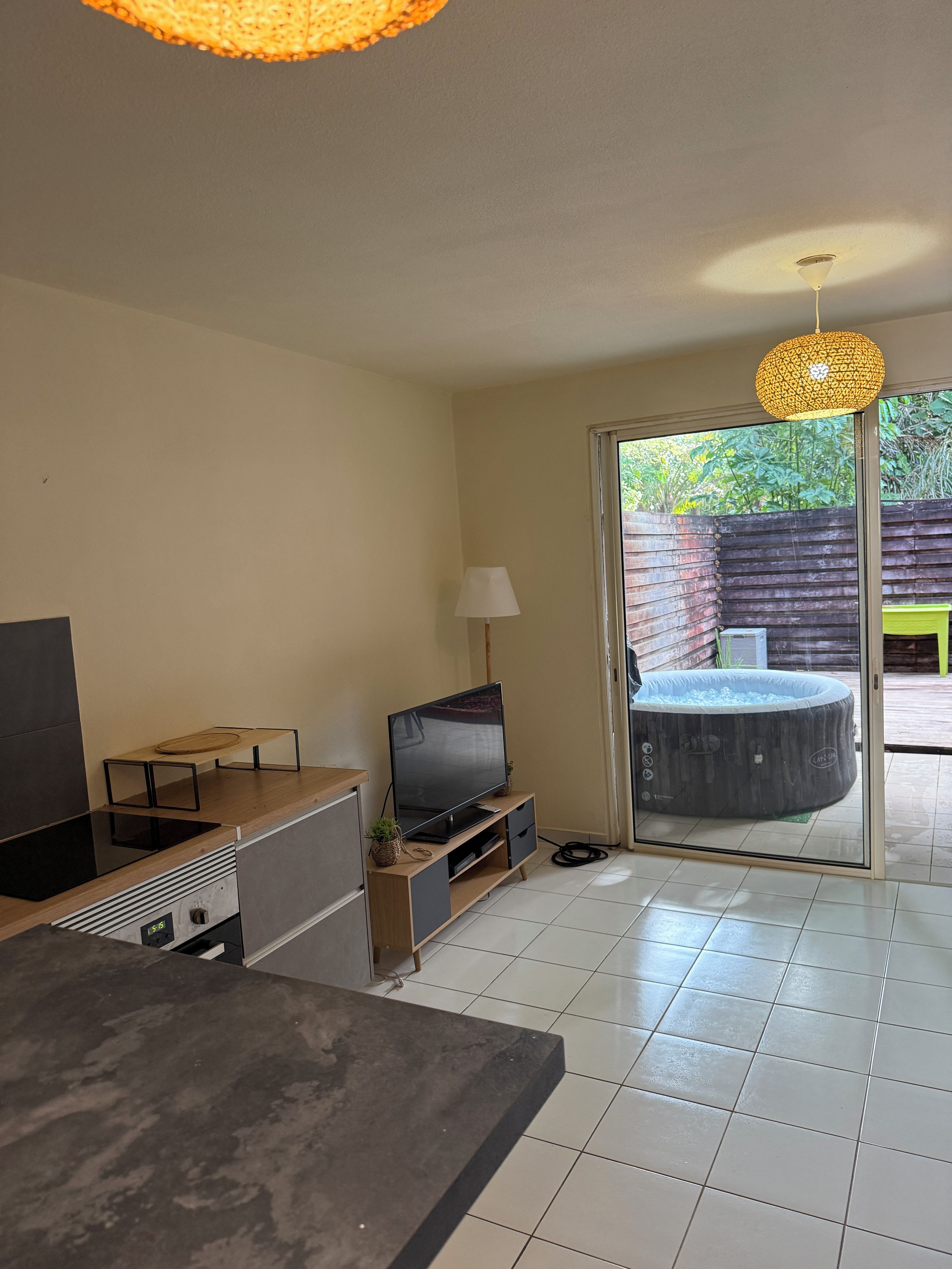 Een moderne woonkamer met een flatscreen televisie, een salontafel en een glazen schuifdeur naar een buitenzwembad.