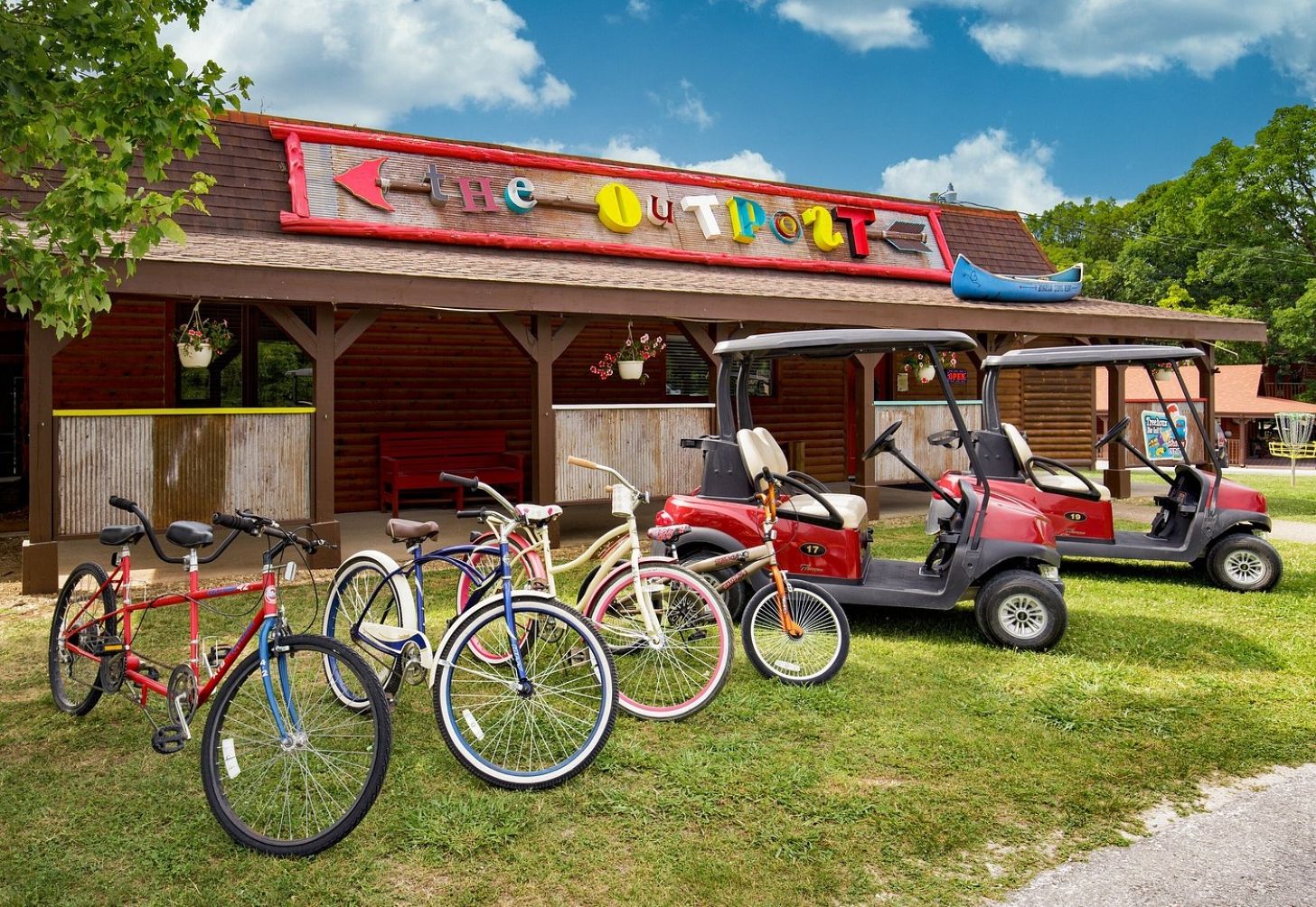 Ein Gebäude mit einem Schild, auf dem 'The Out Door' steht, und einem Golfwagen, der vor der Tür geparkt ist.