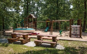 A playground with a boat-shaped slide, swings, and picnic tables. - Branson | Group Ozarks Retreat | Pools + Fitness | 3BR • Sleeps 8 (Ridgedale)