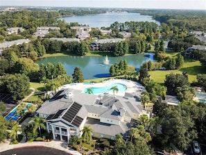 A residential area with a large swimming pool, a fountain, and a lake in the background. - Spacious Ground Floor Condo With Pool View! (Davenport)