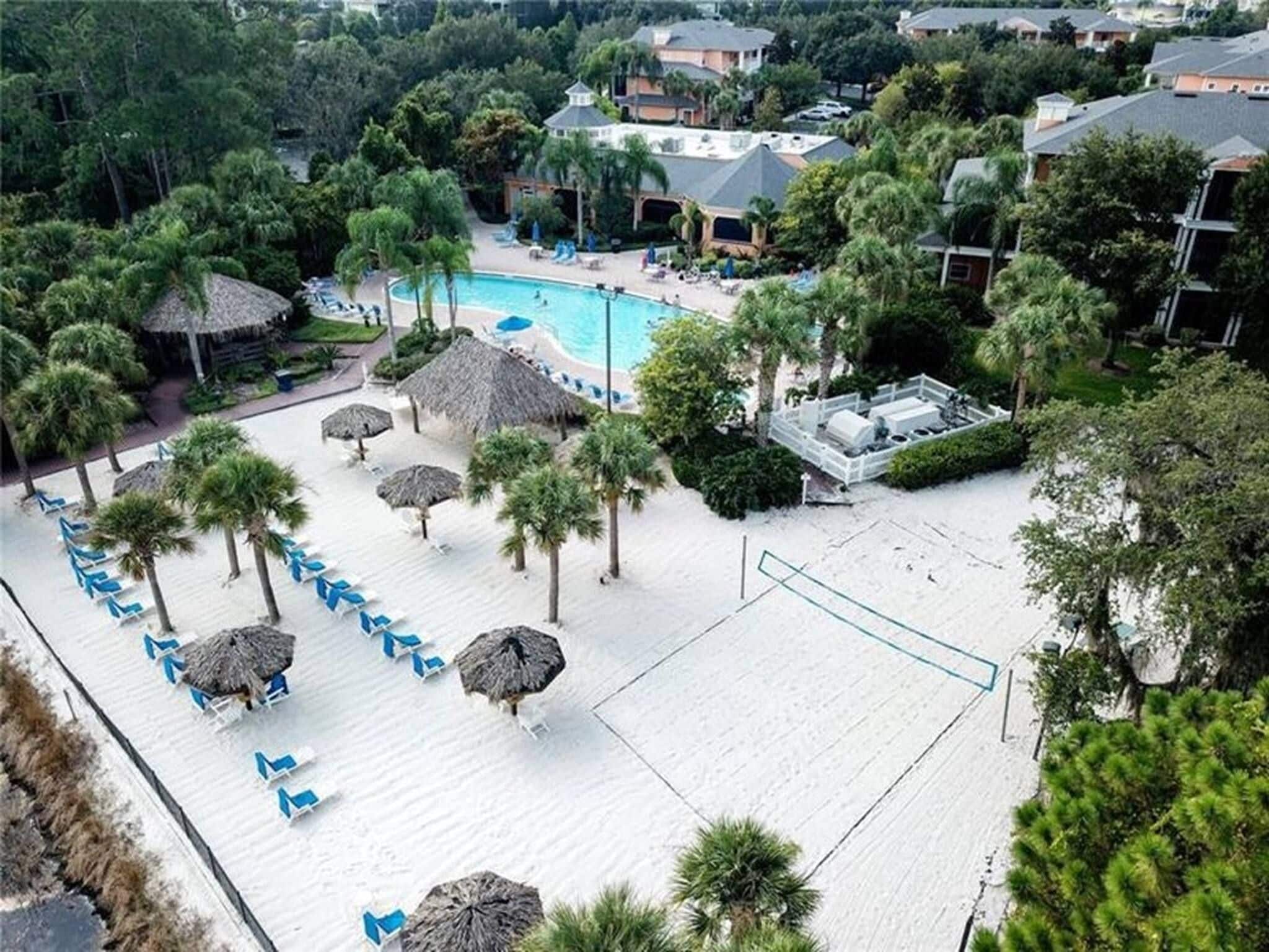 A resort with a swimming pool, lounge chairs, and palm trees.