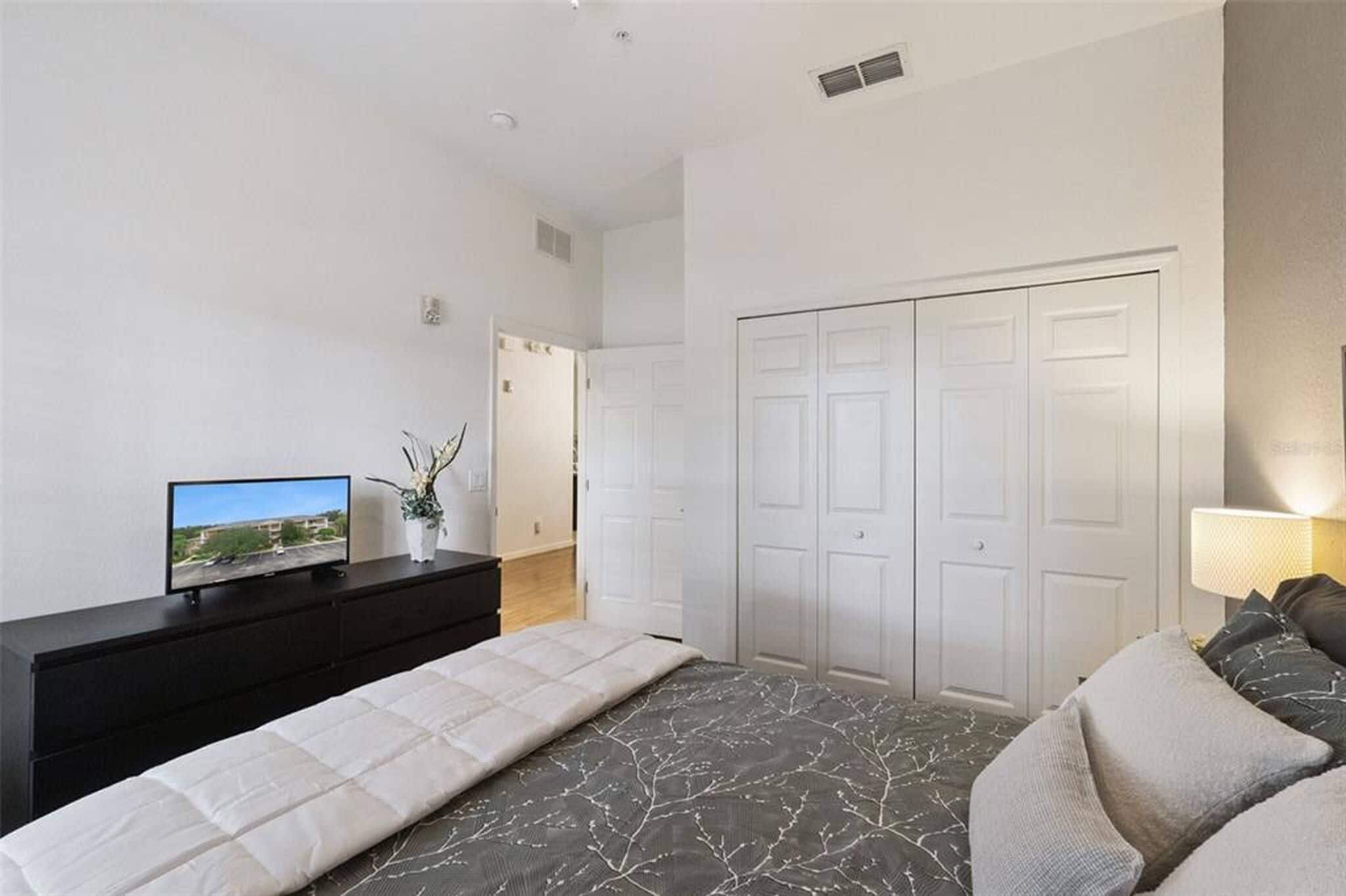 A bedroom with a bed, a TV, a dresser, and a closet.