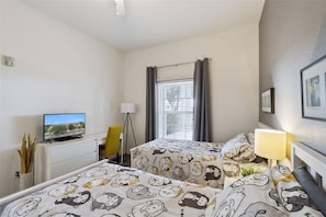 A hotel room with two beds, a television, a desk, and a window with curtains. - Spacious Ground Floor Condo With Pool View! (Davenport)