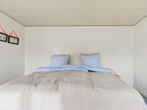 Una camera da letto con un letto, due cuscini e una cornice appesa al muro.