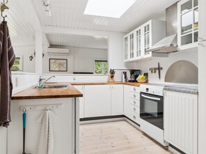 Una cucina moderna con mobili bianchi, un piano di lavoro in legno e un lucernario.