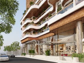 Et moderne hotel med flere etager, med altaner med planter, store vinduer og en rummelig lobby.