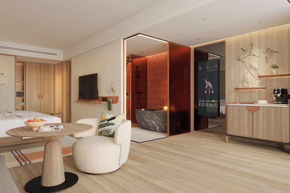 Et moderne hotelværelse med seng, siddeplads med bord, TV, badeværelse og tekøkken.