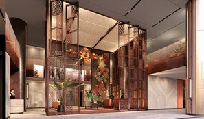 En lobby med receptionsdisk, dekorative paneler og en stor plante.