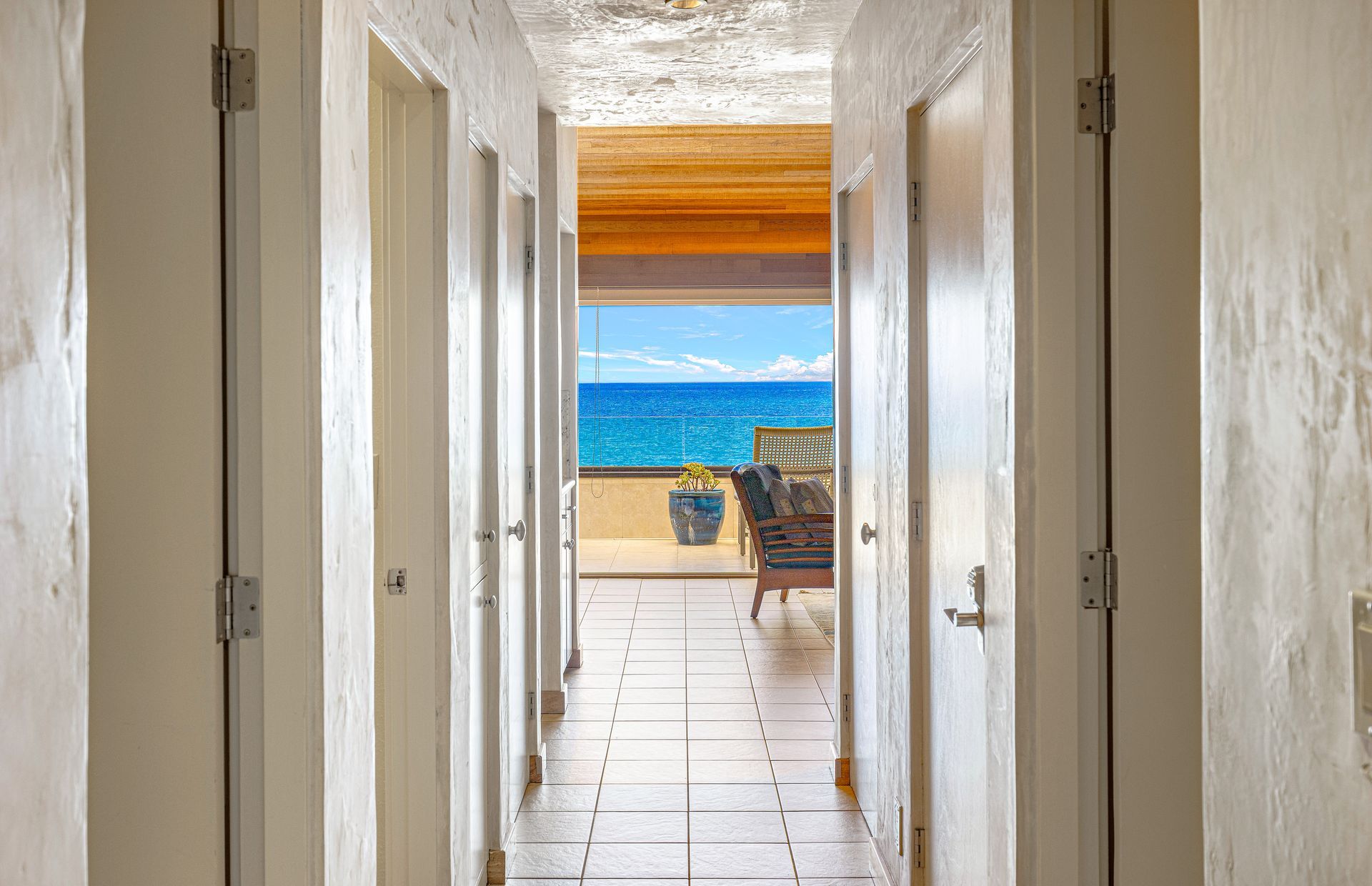 A corridor leading to a balcony with a view of the ocean.