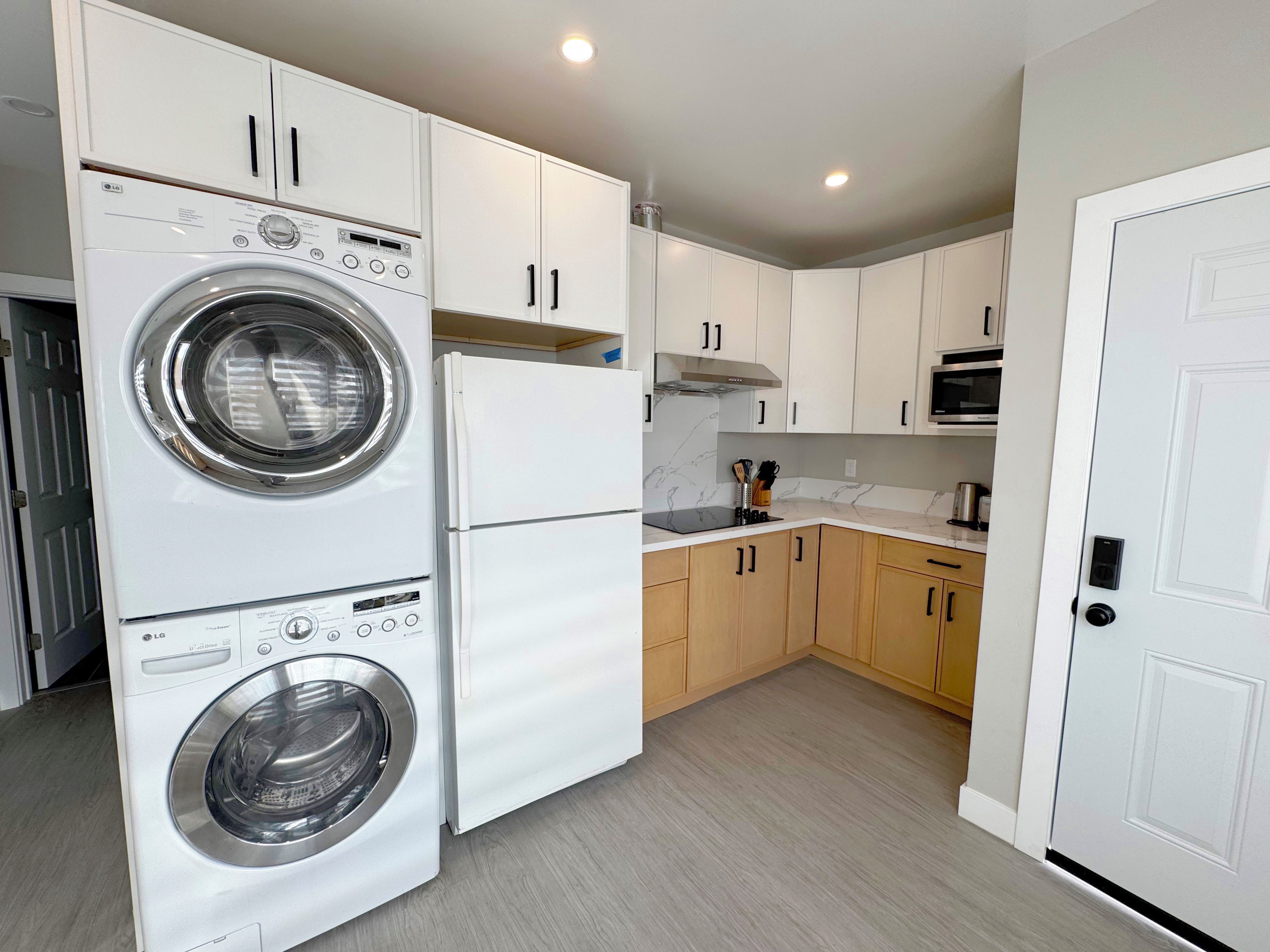 A compact kitchen with a built-in washer and dryer, a microwave, and wooden cabinets.