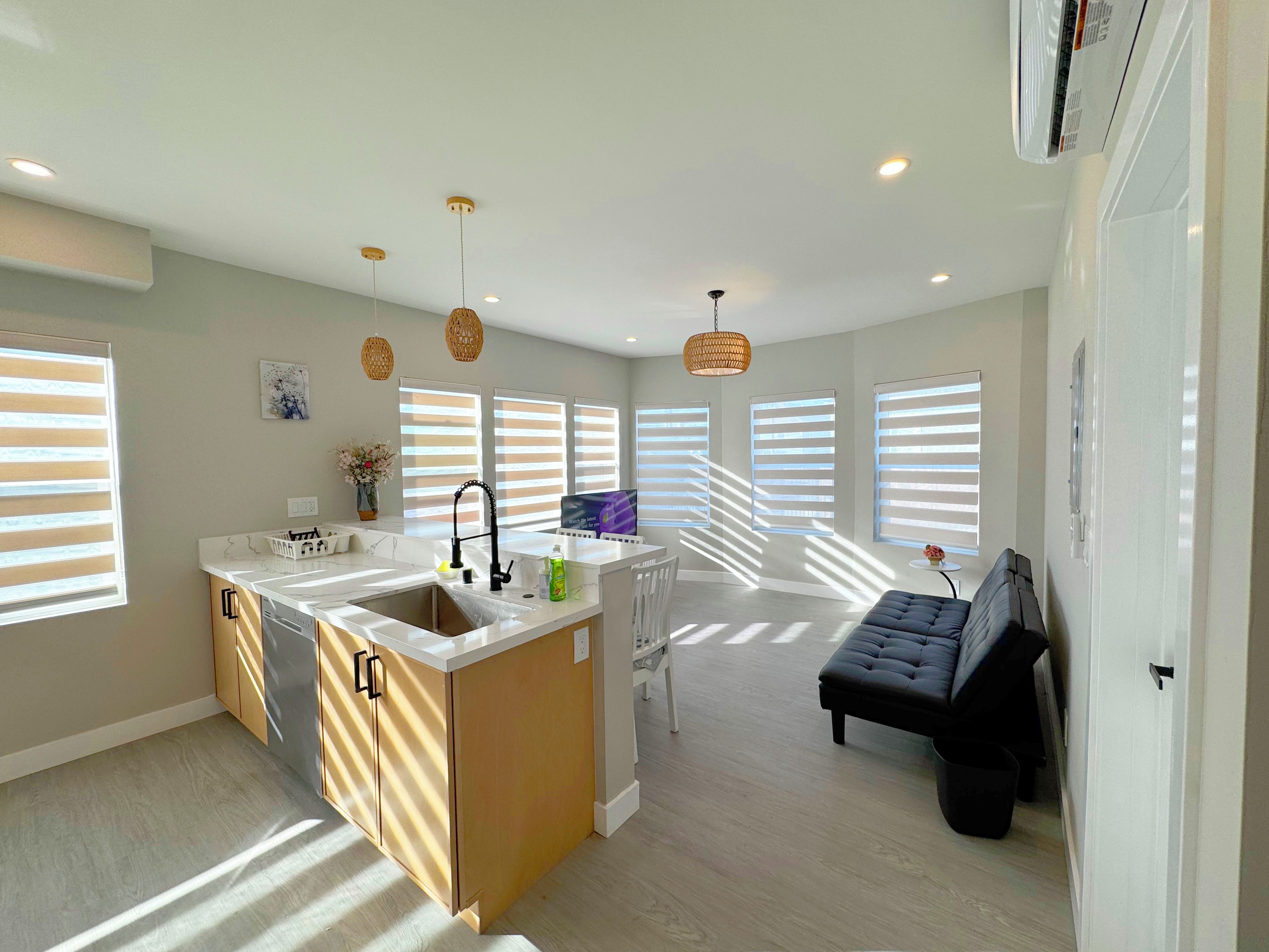 A modern kitchen with a central island, built-in appliances, and a dining area with a sofa.