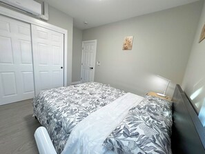 Ein Schlafzimmer mit Bett, Schreibtisch, Stuhl und einer Wand-Klimaanlage.