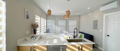 A modern kitchen with a central island, built-in appliances, and a dining area with a bench.