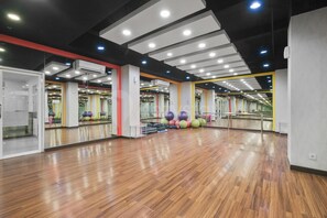 Ein großzügiger Fitnessraum mit Holzboden, Spiegelwänden und Trainingsgeräten.