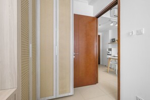 Ein Zimmer mit Holztür, weißer Wand und Küchenbereich mit weißem Tisch und Stühlen.