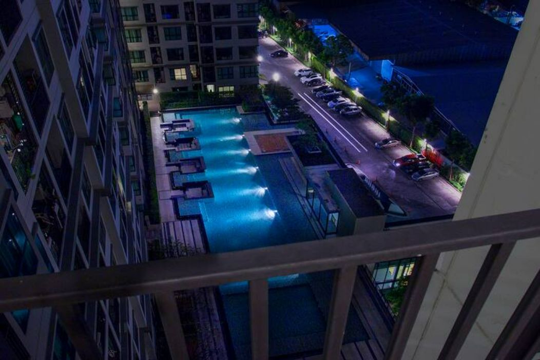 A nighttime view of a hotel with a swimming pool, multiple floors, and a parking area.