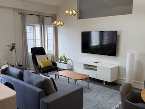 A modern living room with a flat-screen TV, a sofa, a coffee table, and a potted plant. - Hidden Heritage Loft – Architect-Designed Northbridge Stay (Northbridge)