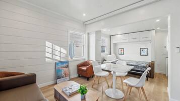 Uma sala de estar moderna com sofá, mesa de centro e área de jantar com cadeiras e mesa.
