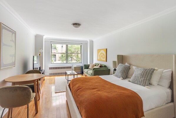 Ein Hotelzimmer mit Bett, Schreibtisch, Stuhl, Fenster und Heizkörper.