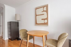 A room with a round wooden table and two chairs, a cabinet, and a wall-mounted artwork. - Blueground | Central Park West, gym, nr Central Park (New York)