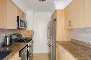 Eine Küche mit Granit Arbeitsplatten, Edelstahlgeräten und Holzschränken.