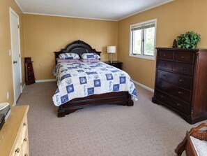 A bedroom with a bed, dresser, nightstand, and a window.