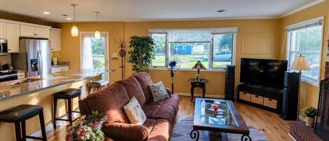 A living room with a brown sofa, a coffee table, and a TV.