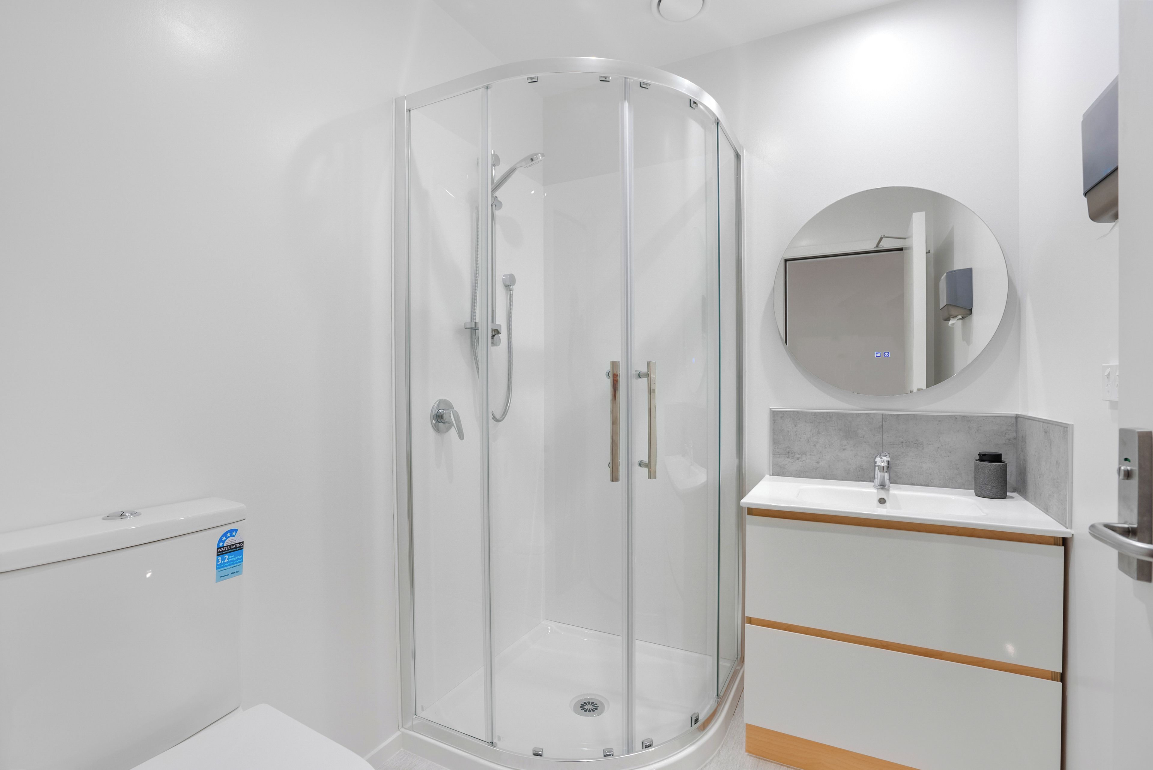 A modern bathroom with a glass shower enclosure, a white sink with a mirror, and a toilet.