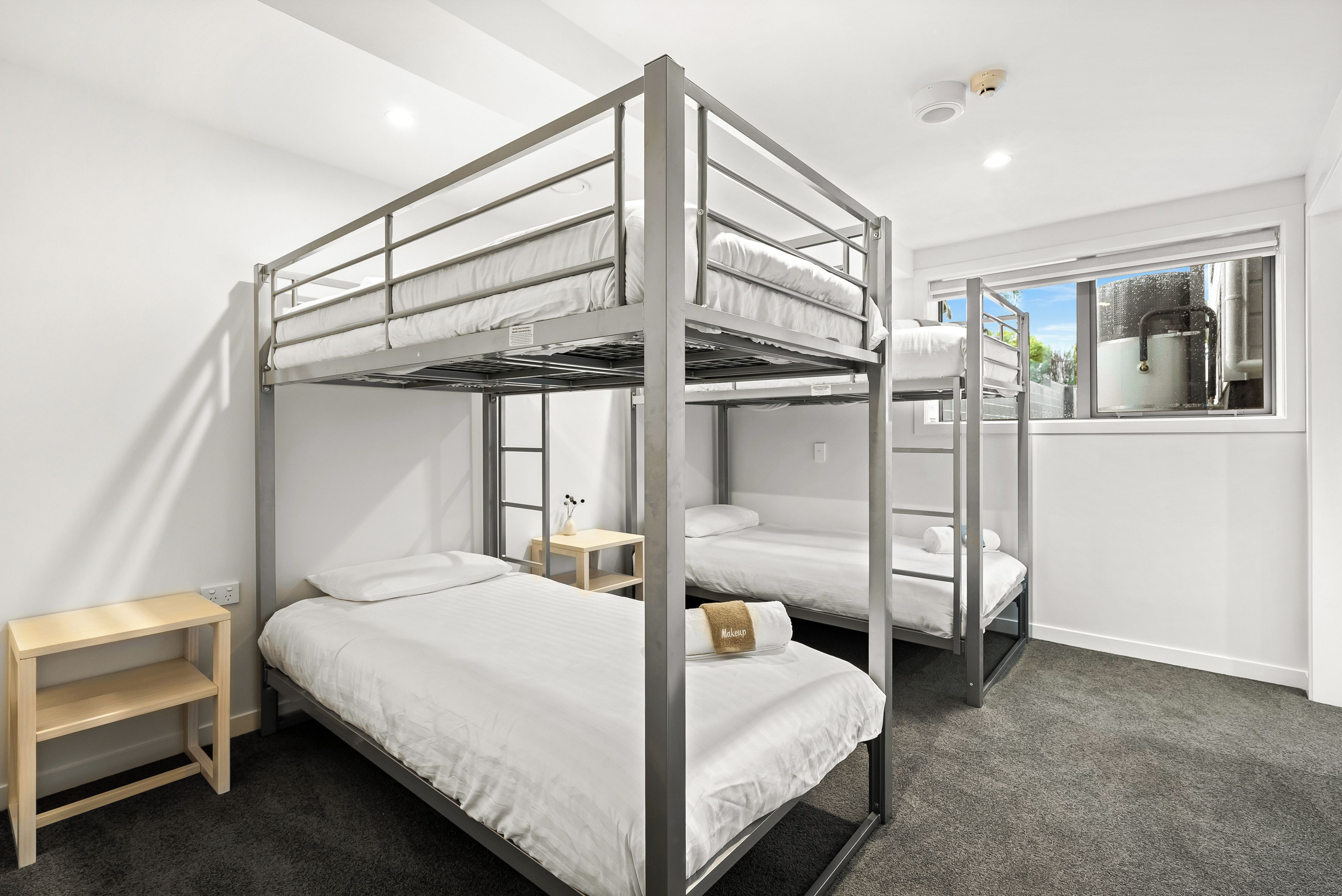 Habitación con literas, una pequeña mesa y una ventana.