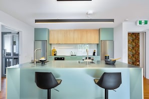 A modern kitchen with a central island, bar stools, and wooden cabinets.