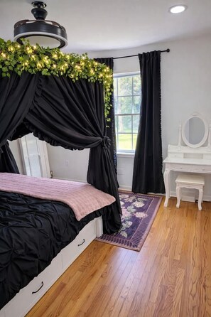 Een slaapkamer met een bed, een kaptafel en een raam met gordijnen.
