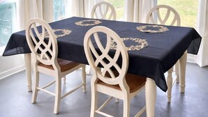 En matplats med ett bord dukat för fyra personer, omgivet av stolar med ett dekorativt, flätat ryggstöd.
