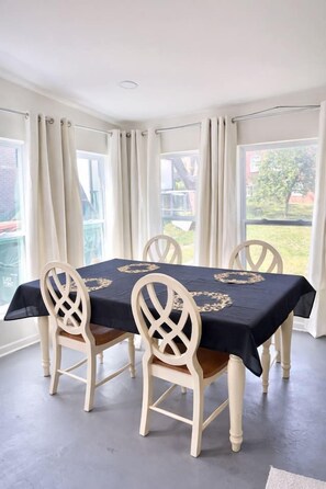 Een eetgedeelte met een tafel voor vier personen, omringd door stoelen met een open rugleuning.