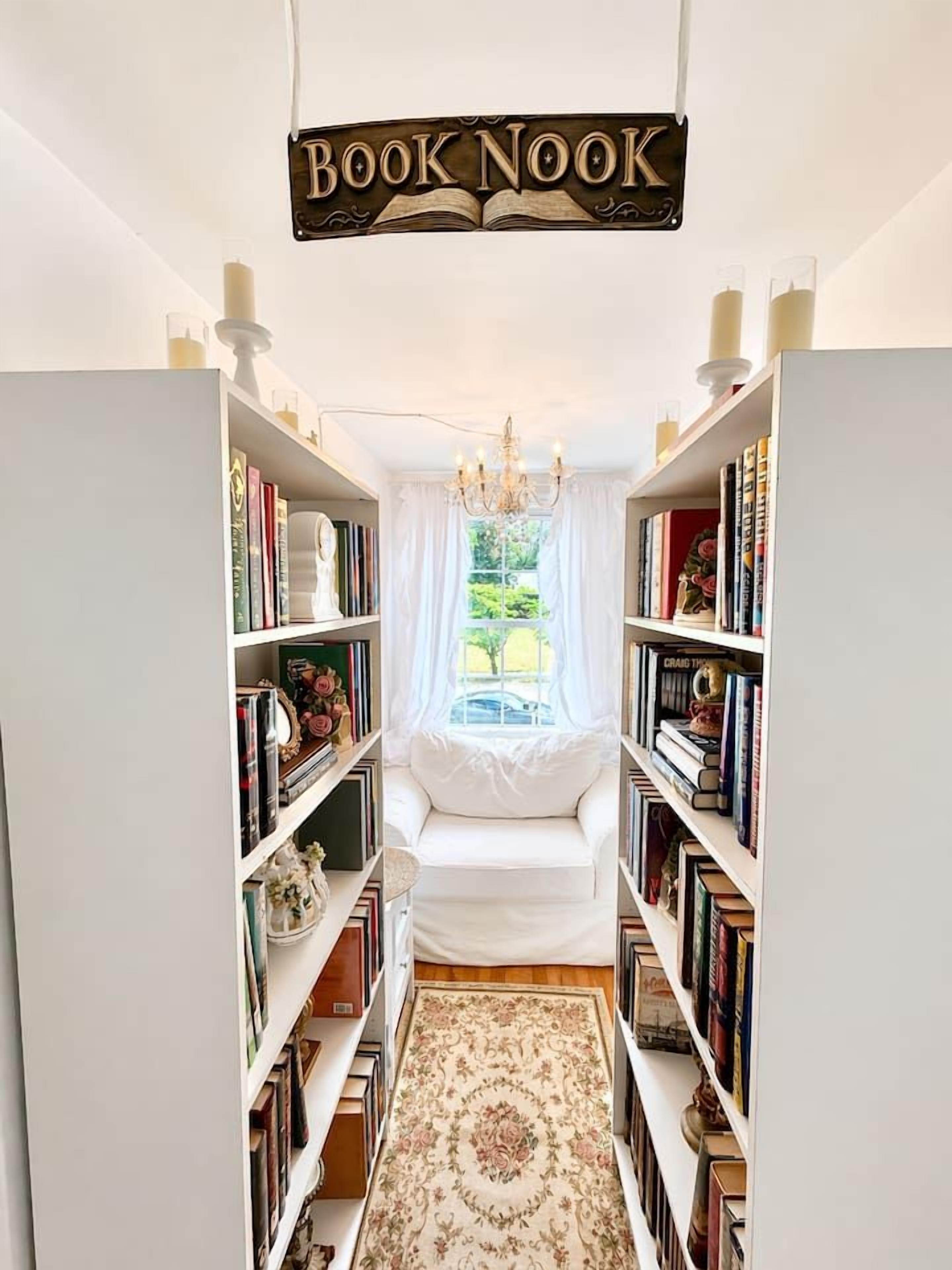 Ein schmaler Flur mit Bücherregalen an beiden Seiten, einem weißen Sofa und einer Kristallleuchtre.