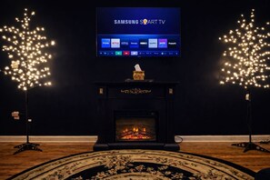 A Samsung Smart TV mounted above a fireplace with decorative lights on either side.