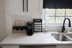 A kitchen with a coffee bar, a coffee machine, and a glassware rack.