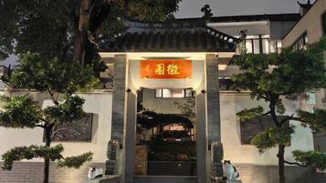 Ein Eingang eines traditionellen Gebäudes mit einem Ziegeldach, einer Steintreppe und einem Schild mit chinesischen Schriftzeichen.
