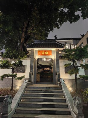A traditional building entrance with a tiled roof, a stone staircase, and a sign with Chinese characters.