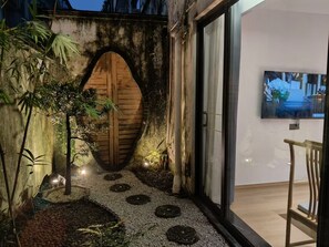 A modern interior with a wooden door, a small garden area with pebbles and plants, and a television mounted on the wall. - HUIYUAN Wushan (Guangzhou)