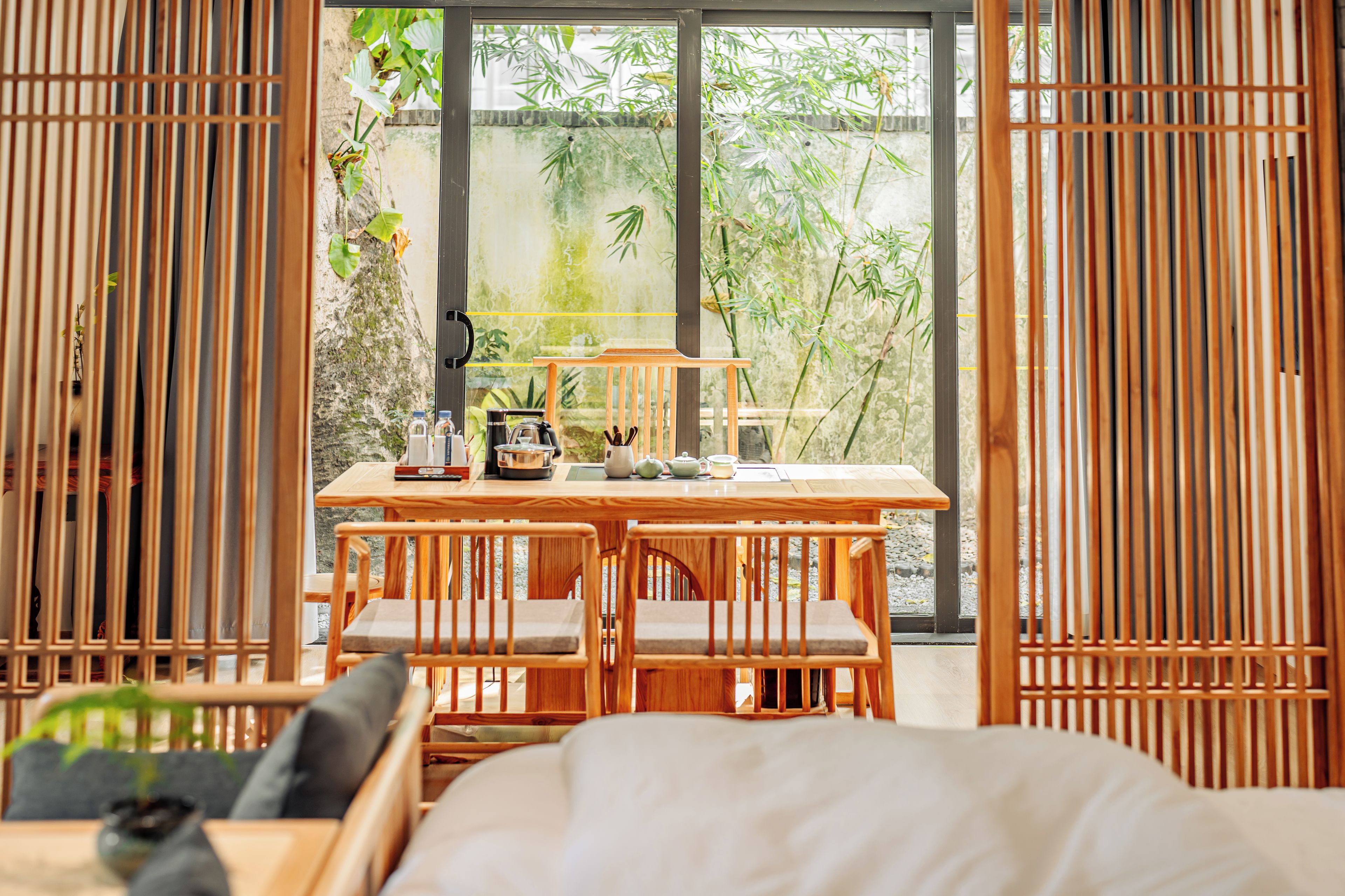 A room with a wooden table, chairs, and a view of greenery outside.