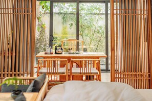 Una habitación con una mesa de madera, sillas y vistas al exterior con vegetación.
