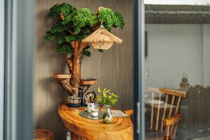 Ett träbord med ett dekorativt träd, en lampa och en liten vas med en växt.