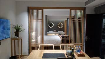 Habitación de hotel moderna con un separador de madera, una cama, un escritorio y vista al baño.