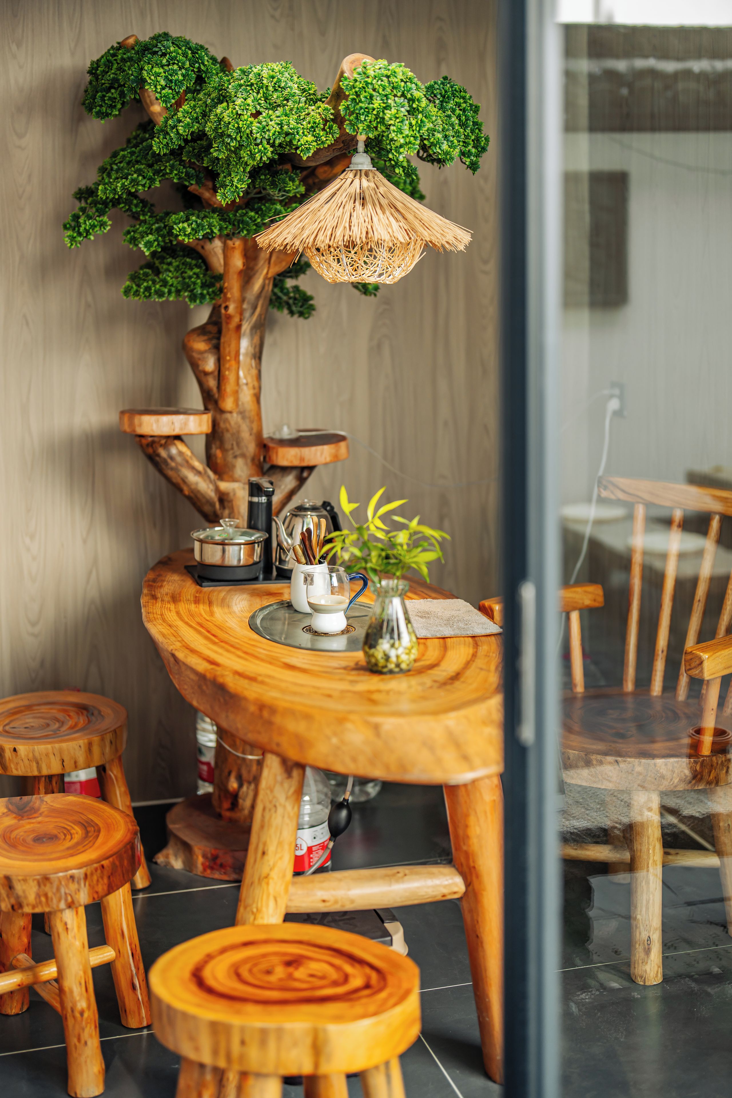 Ein Holztisch mit einer Baumdekoration in der Mitte, umgeben von Holzschemeln und -stühlen.