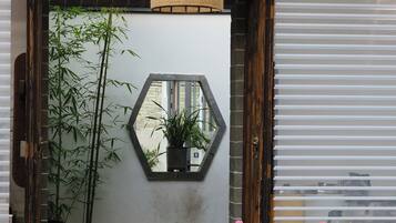 A modern interior with a hexagonal mirror, bamboo plants, and a wooden table.