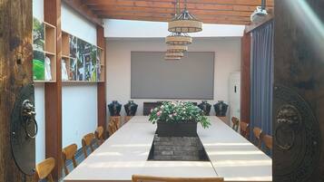 Un comedor con una mesa larga, sillas, una lámpara colgante y una planta en maceta.