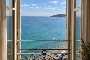 A view from a balcony with a railing, overlooking a calm sea with boats and a distant coastline. - Horizon azur, Menton, France (Menton)